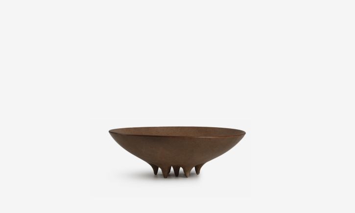 Terracotta ceramic vase features soft oval forms and small conical legs, serving as a sculptural piece.